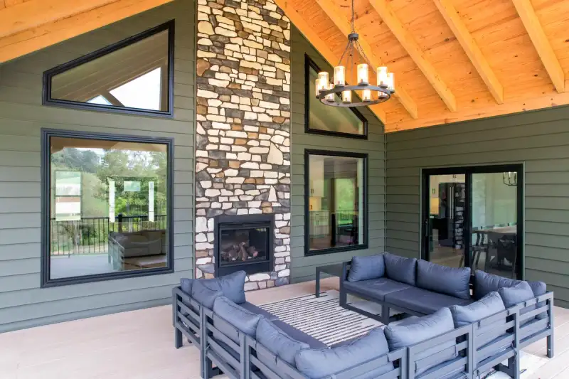 Covered patio with stone fireplace, windows, and siding in Western NC